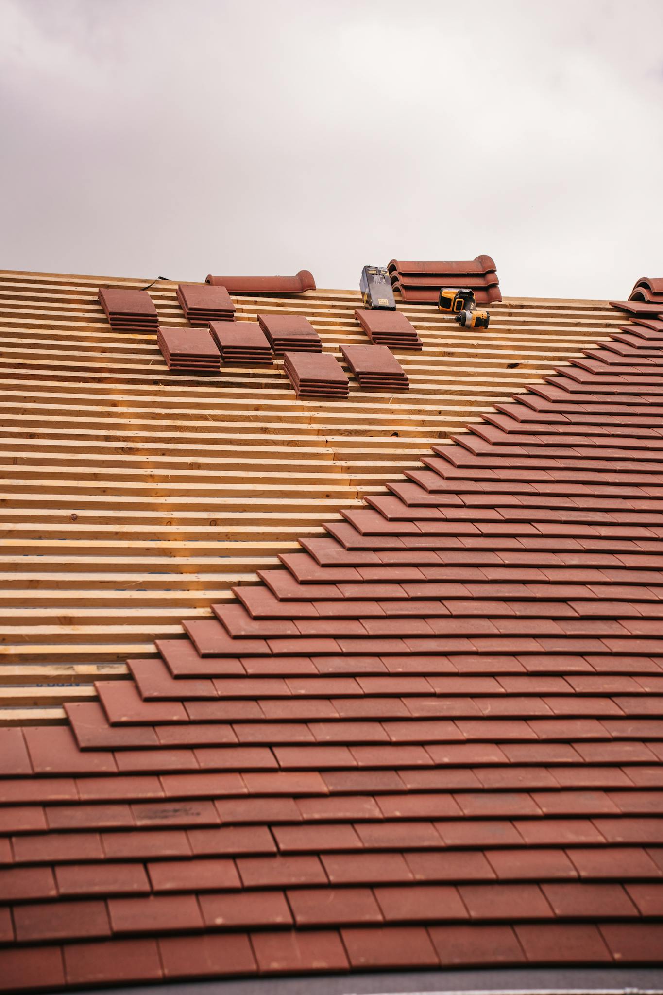 Partial installation of a terracotta tile roof on a building in progress.